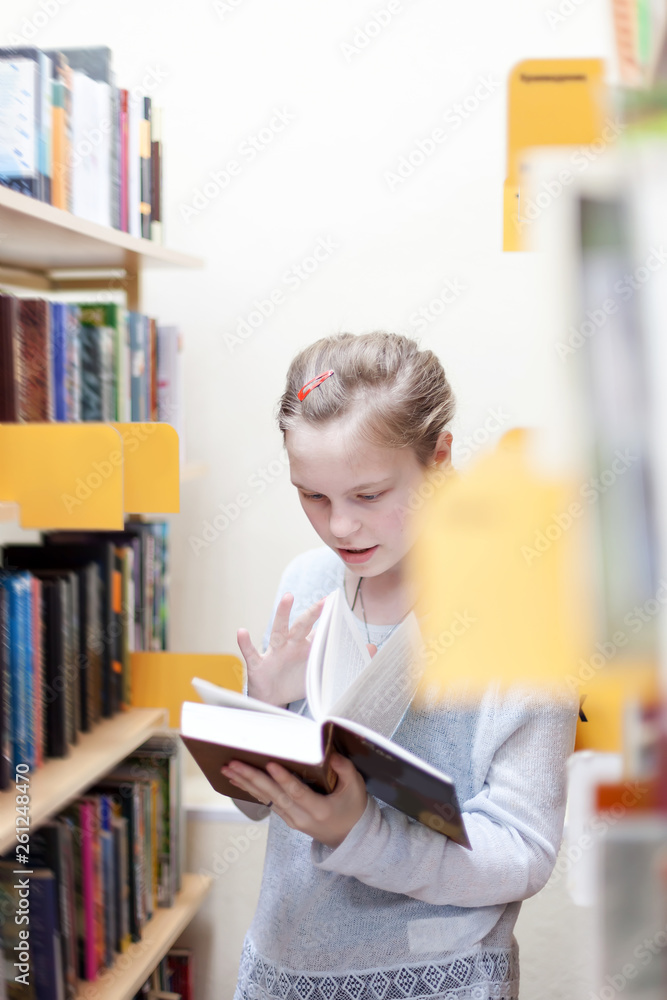 girl of 13 years old choosing book in library. girl of 13 years old choosing book in library.