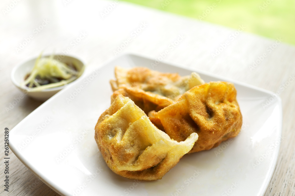 Chinese dumplings snack with soy sauce and ginger. On wooden table and green grass background. Chinese dumplings snack with soy sauce and ginger. On wooden table and green grass background.