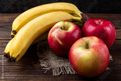 Banana and red apple on dark wooden background.  photo