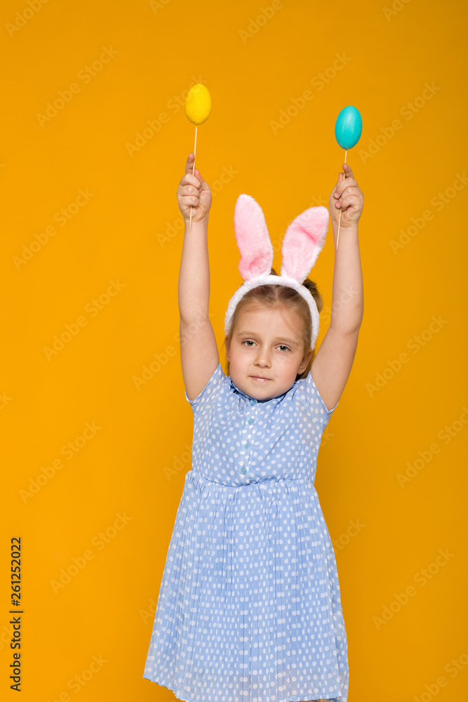 Portrait of cute little child girl with Easter bunny ears holding colorful eggs on yellow background. Happy easter Portrait of cute little child girl with Easter bunny ears holding colorful eggs on yellow background. Happy easter