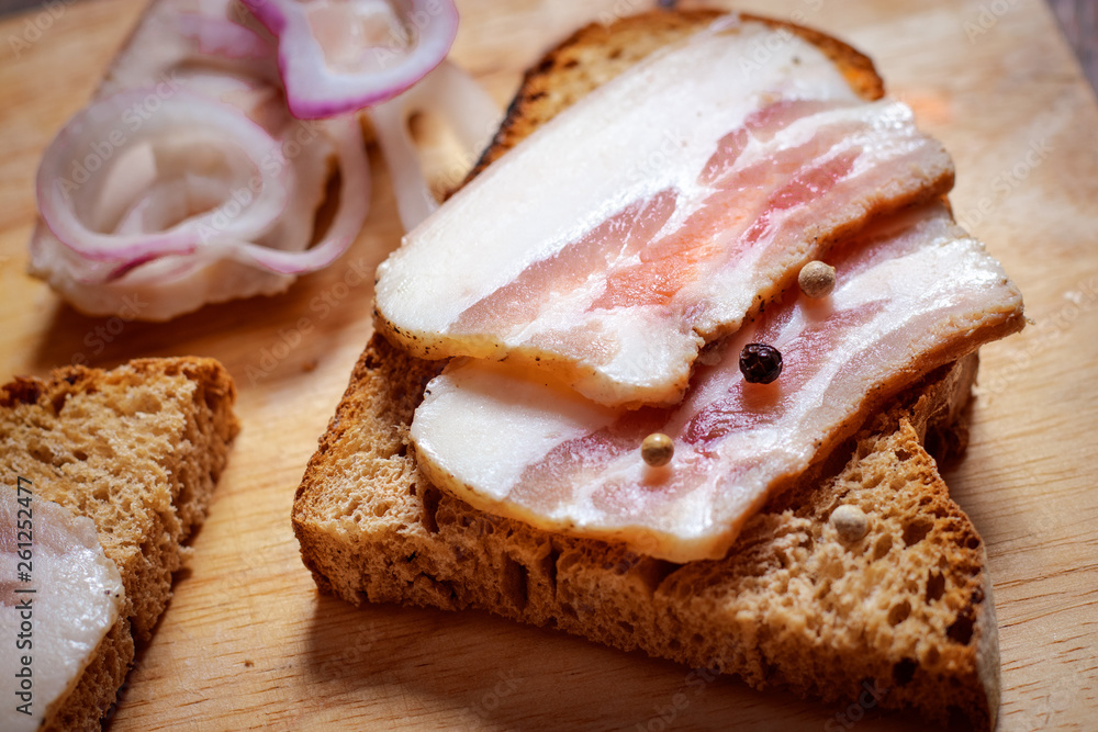 Lard sandwich with black bread and onions on a wooden board. Lard sandwich with black bread and onions on a wooden board.