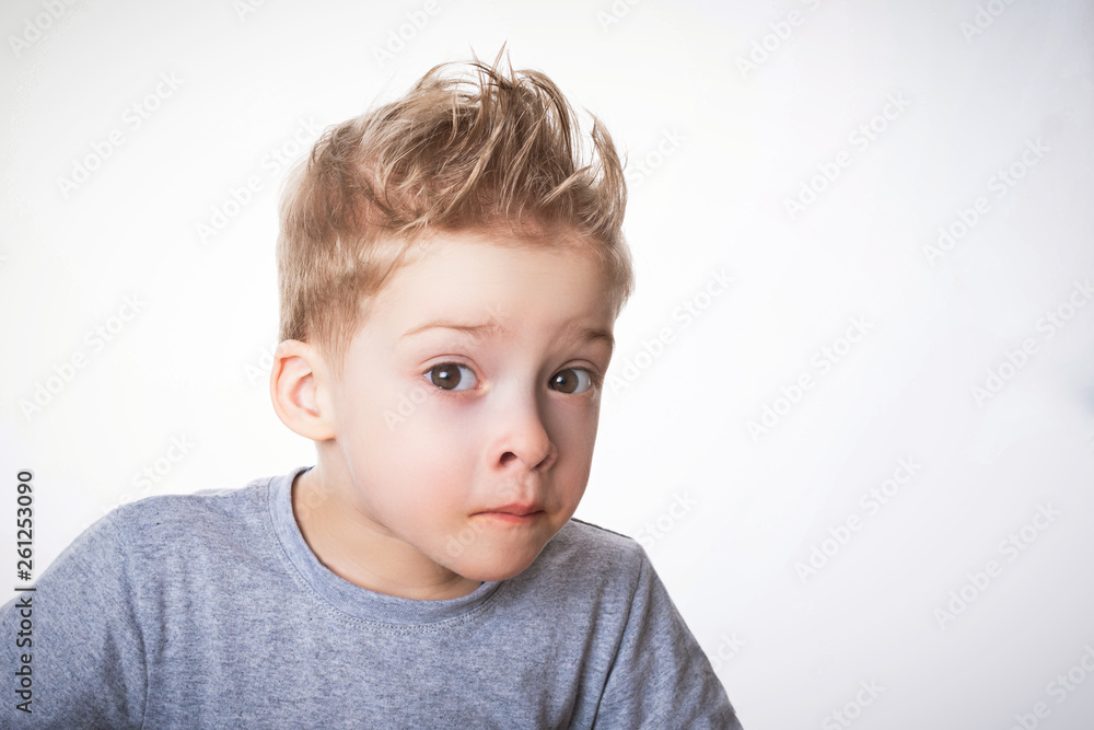 preschool-age boy in a gray t-shirt looks questioningly with wide eyes preschool-age boy in a gray t-shirt looks questioningly with wide eyes