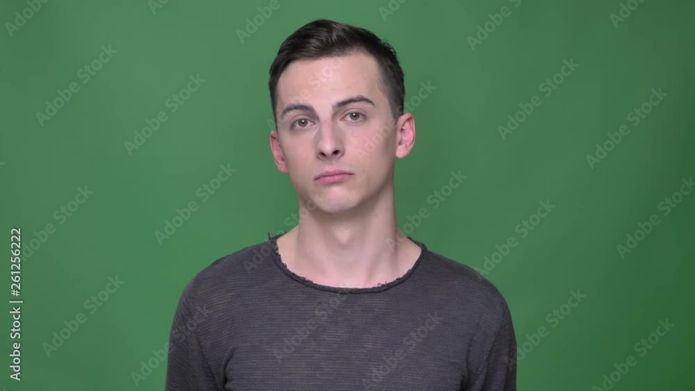 Closeup shoot of young handsome caucasian male nodding saying yes looking straight at camera with background isolated on green Closeup shoot of young handsome caucasian male nodding saying yes looking straight at camera with background isolated on green