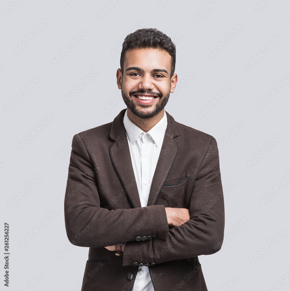 Portrait of handsome smiling young man with folded arms. Laughing joyful cheerful men with crossed hands studio shot. Isolated on gray background Portrait of handsome smiling young man with folded arms. Laughing joyful cheerful men with crossed hands studio shot. Isolated on gray background