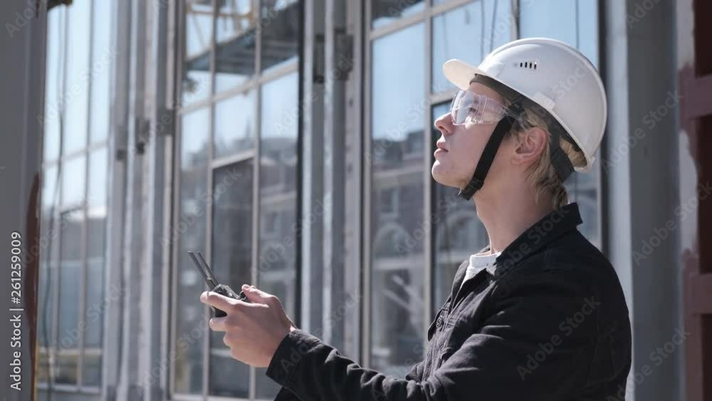 Caucasian man in hard hat and safety glasses. Portrait of engineer construction worker in helmet controlling flying copter. Modern technologies in construction, and architecture Caucasian man in hard hat and safety glasses. Portrait of engineer construction worker in helmet controlling flying copter. Modern technologies in construction, and architecture