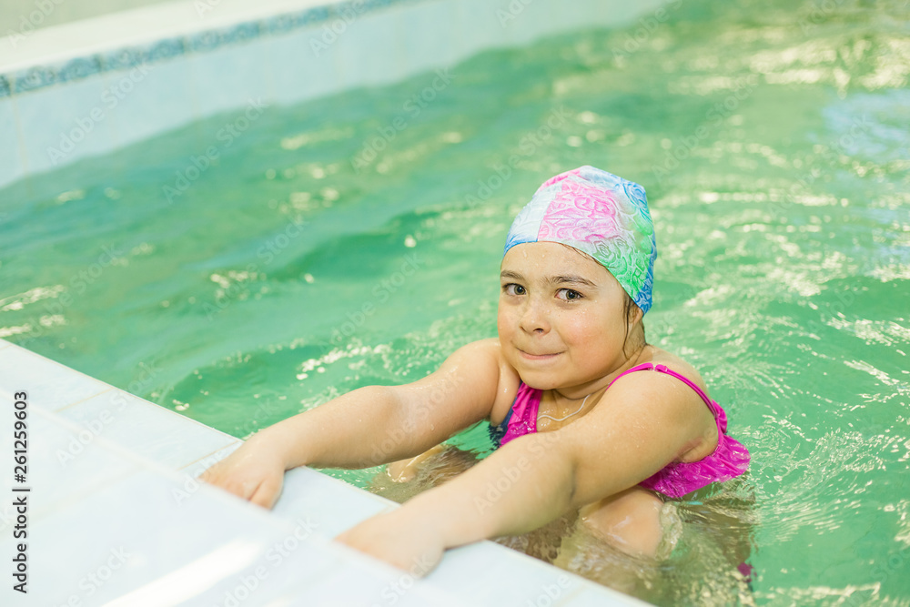 Preschooler sport girl in swimming pool in swim wear lerning to swim and have fun. Sport, pool, childhood concept