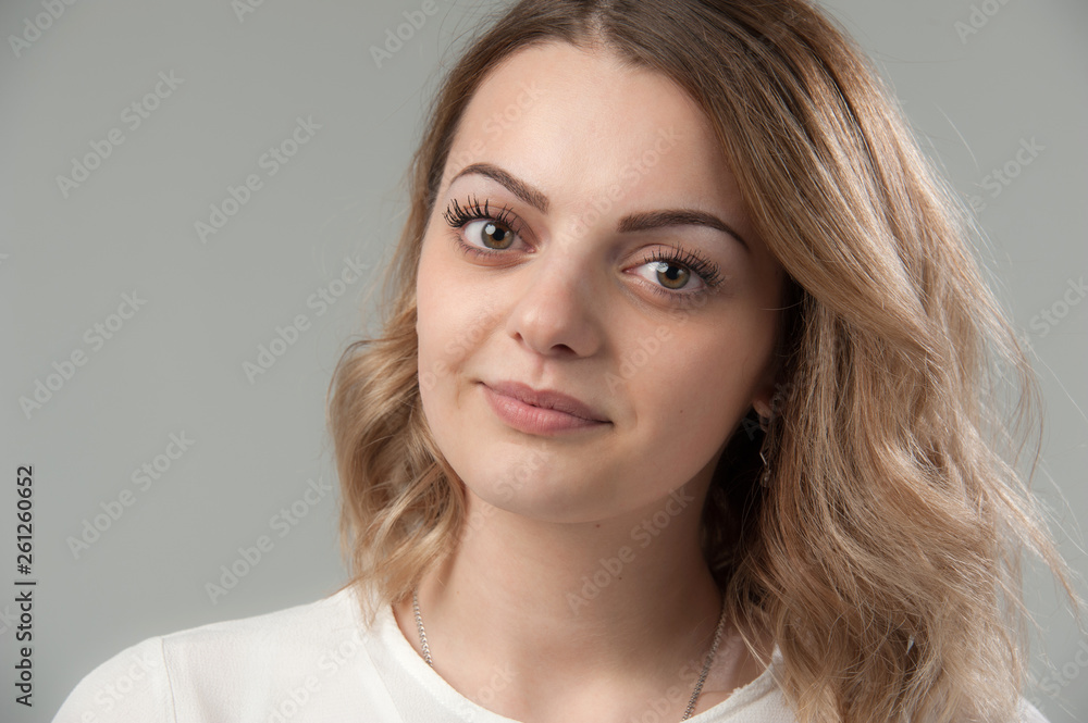 Portrait of a young attractive woman with blond hair on a neutral gray background. Portrait of a young attractive woman with blond hair on a neutral gray background.