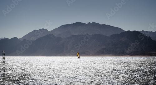 surfer rides in the Red Sea against the backdrop of the coast with high rocky mountains in Egypt Dahab
