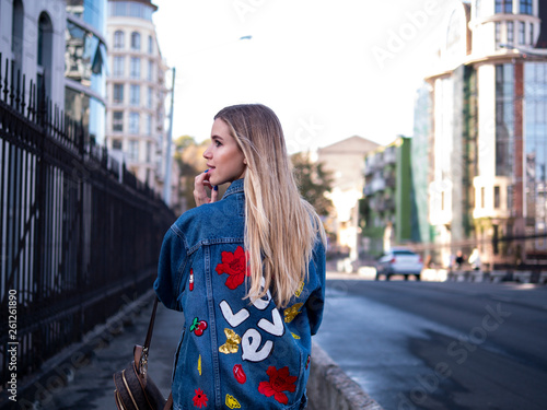 cute blonde teen with flowing hair in a denim jacket on the bridge outdoor