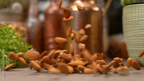 MACRO, DOF: Ripe organic unpeeled brown almonds falling onto the kitchen table.