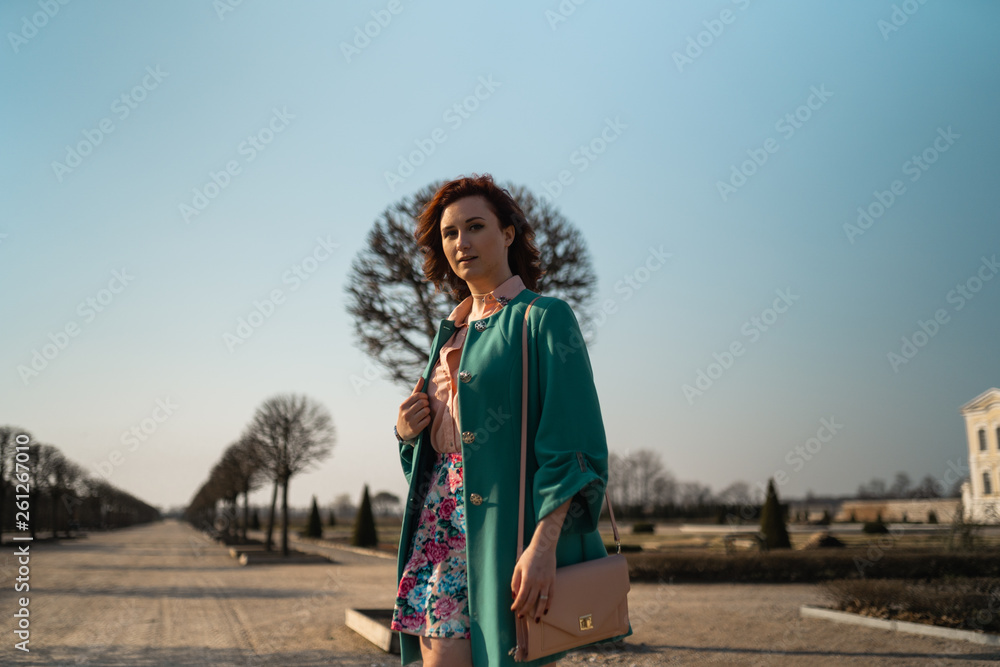 Young fashion lover woman waling in a park wearing vivid green jacket and a colorful skirt