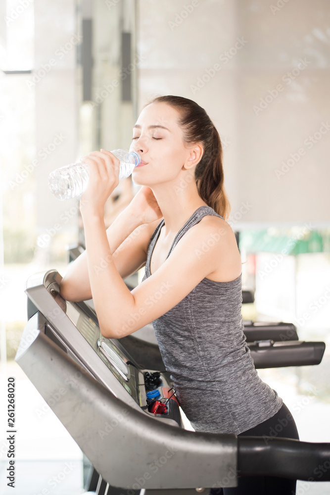 Pretty young sport woman is drinking water on treadmill in gym, Healthy lifestyle Pretty young sport woman is drinking water on treadmill in gym, Healthy lifestyle