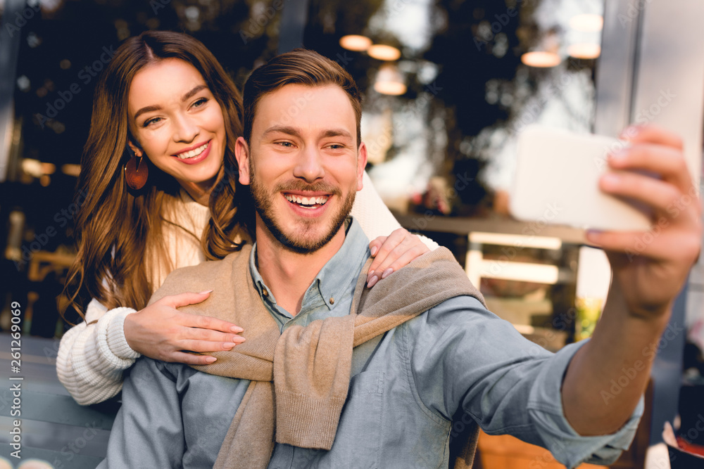 selective focus of cheerful man taking selfie with happy girlfriend selective focus of cheerful man taking selfie with happy girlfriend