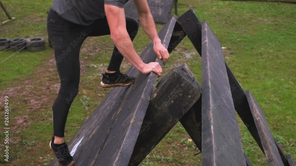 Male participant in an obstacle course climbing a pyramid obstacle Male participant in an obstacle course climbing a pyramid obstacle