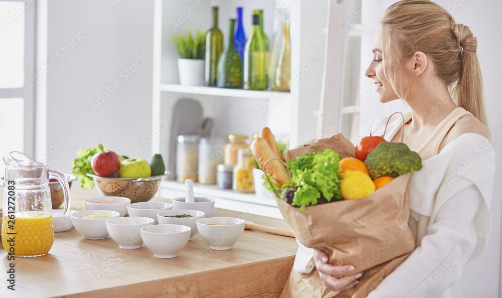 Young woman holding grocery shopping bag with vegetables Standi