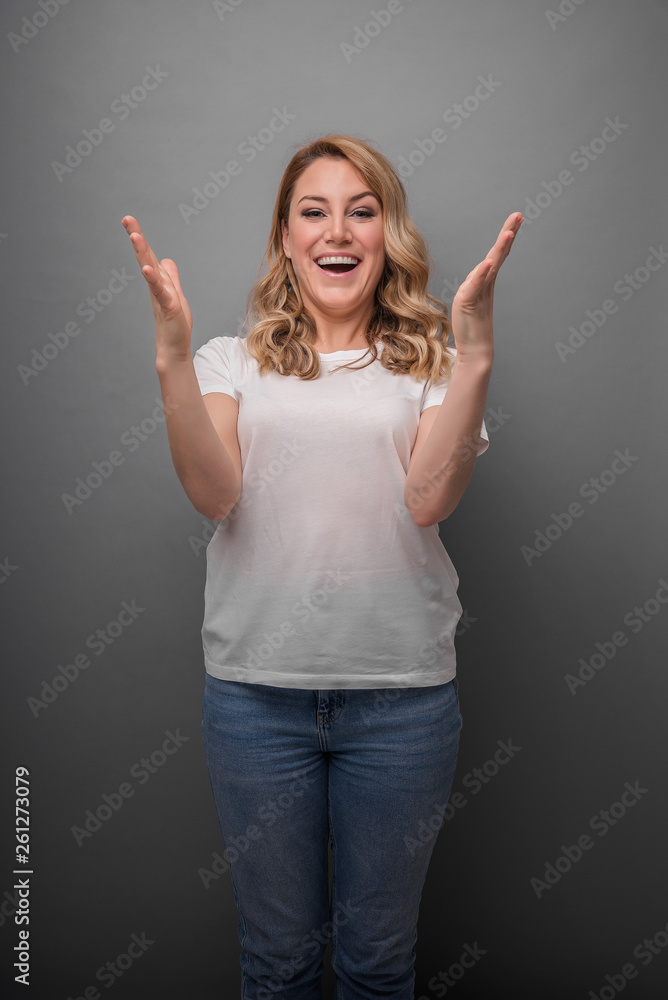 Beautiful young woman celebrating a victory. A woman emotionally expresses joy or success on a gray background. Beautiful young woman celebrating a victory. A woman emotionally expresses joy or success on a gray background.