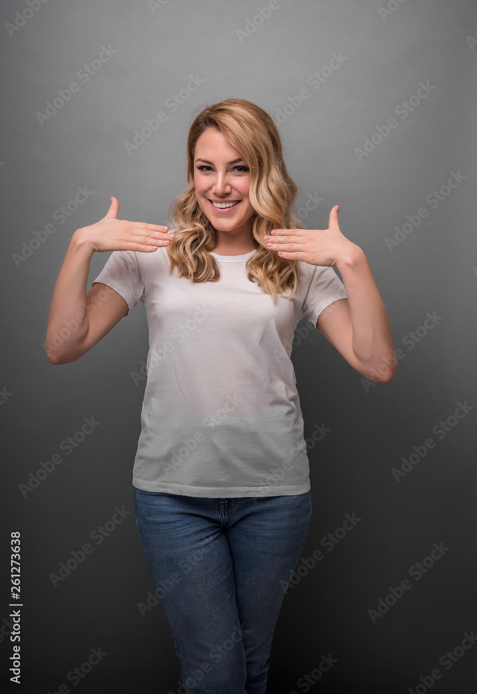 Woman shows on herself posing on a gray background. Woman shows on herself posing on a gray background.