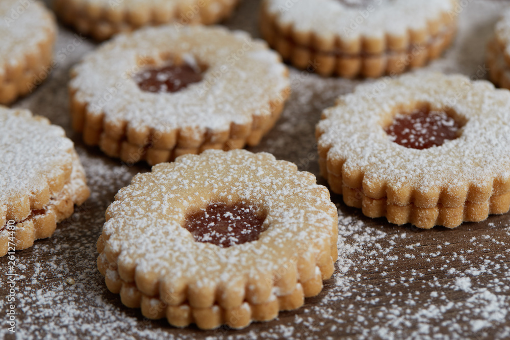 Close up of freshly baked homemade Christmas sugar cookies with jam on a wooden background