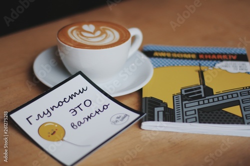 Konstfotografi cup of coffee on the table with magazine with postcard stupidity is important