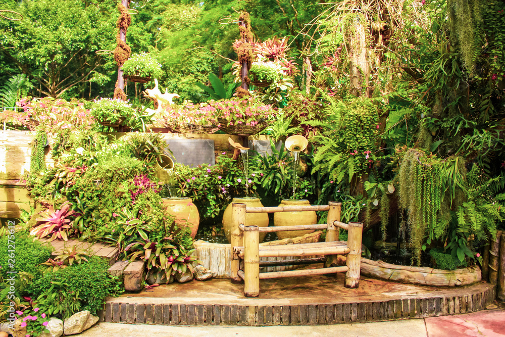 beautiful tropical garden with green plants and decorations, pots and a bench beautiful tropical garden with green plants and decorations, pots and a bench