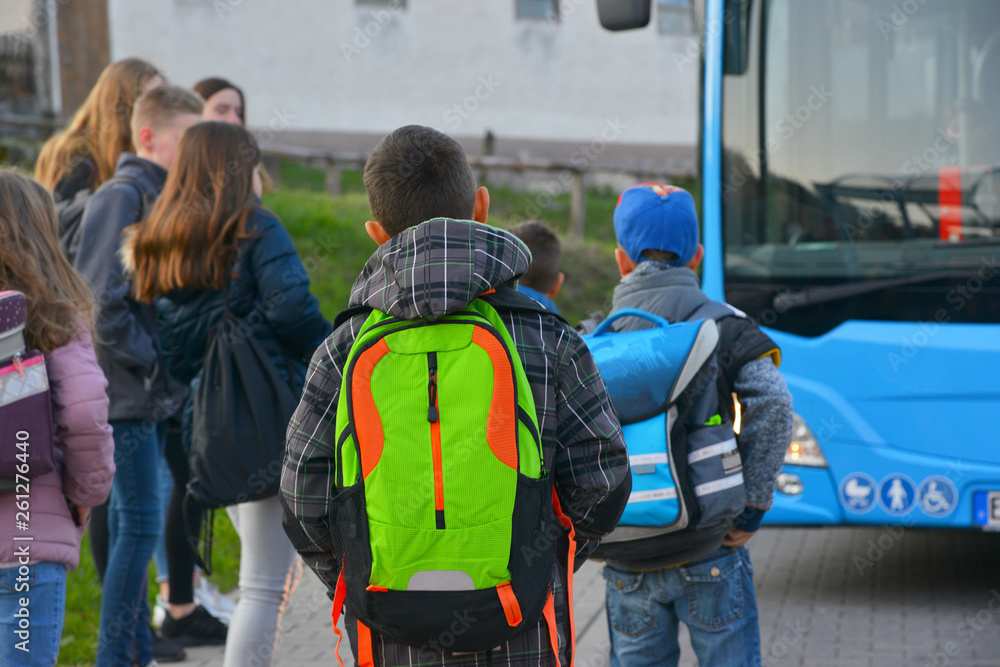 Schüler mit Schulrucksack der Grundschule auf dem morgendlichen Weg zum Schulbus - obrazy, fototapety, plakaty 