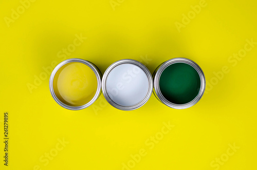Three cans of multicolored paint on a yellow background.