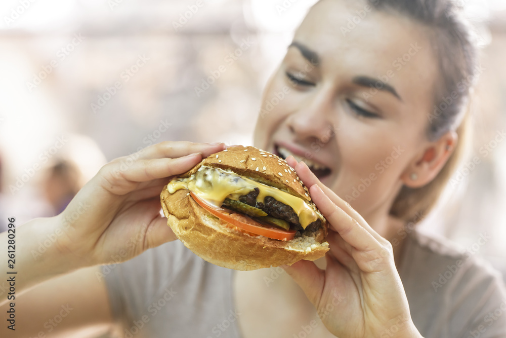 Young woman in cafe eating tasty sandwich Young woman in cafe eating tasty sandwich