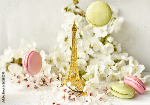The Eiffel Tower figurine among white cherry flowers and sweet multicolored macaroons. Love, romance, spring.