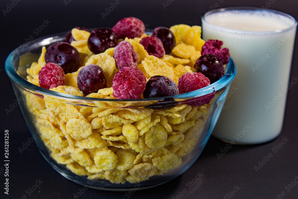 a bowl of cornflakes sprinkled with raspberries and cherries with a glass of milk a bowl of cornflakes sprinkled with raspberries and cherries with a glass of milk
