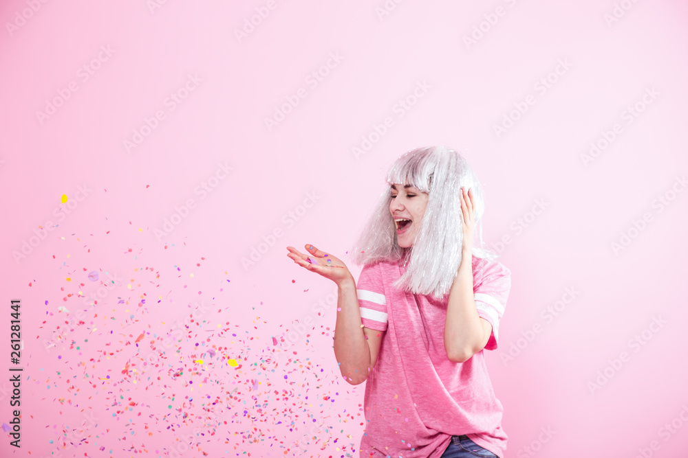 Funny Girl with silver hair gives a smile and emotion on pink background. Young woman or teen girl with confetti