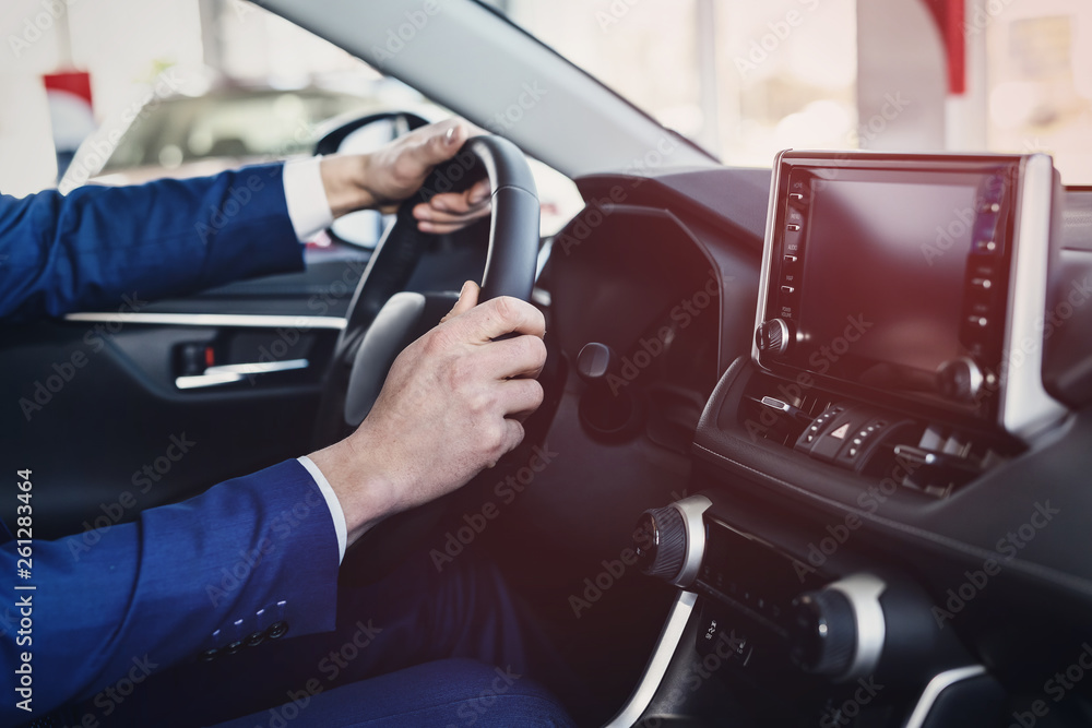 Male hands on steering wheel, car interior