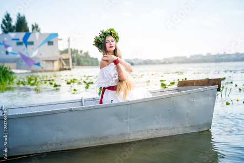 Beautiful girl in national dress in boat on lake