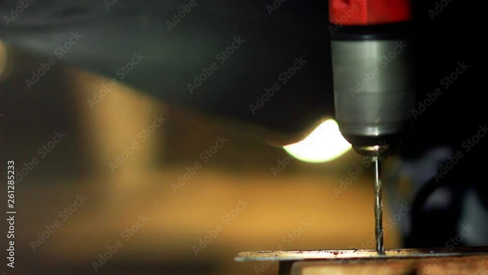 artisan drills a metal sheet with a drill. artisan drills a metal sheet with a drill.