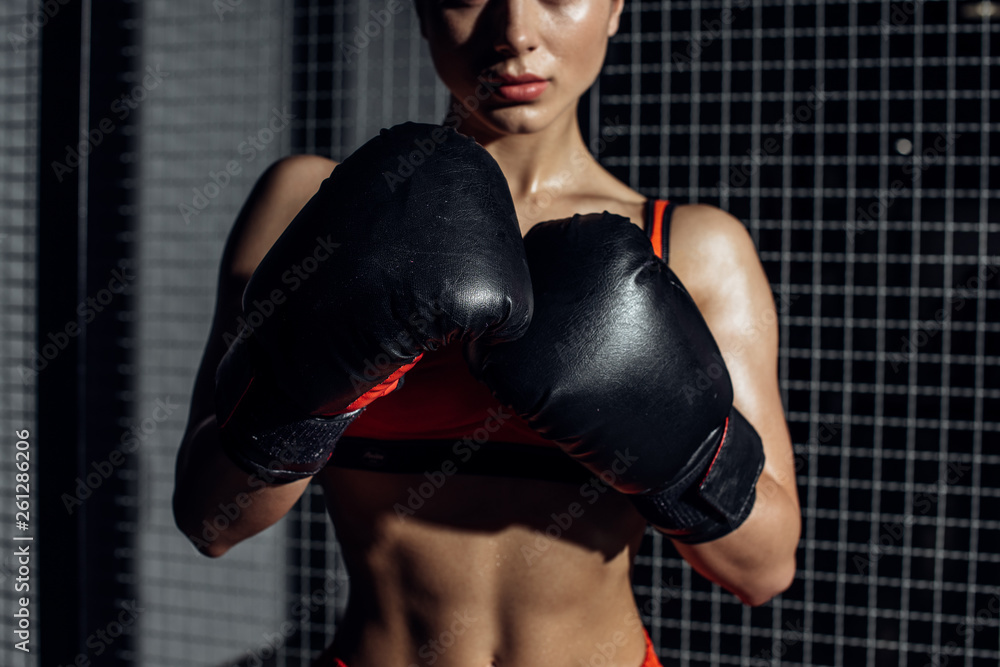 Cropped view of muscular woman in black boxing gloves