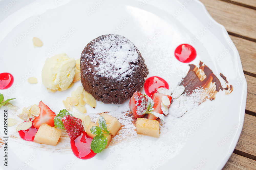 Chocolate lava cake with sugar powder vanilla icecream and diced apple strawberry desserts on white plate top view Chocolate lava cake with sugar powder vanilla icecream and diced apple strawberry desserts on white plate top view