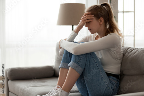 Фототапет Upset woman frustrated by problem sitting on couch, embracing knees,