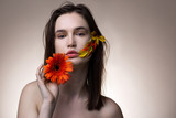 Appealing tender model with orange flower in hand posing