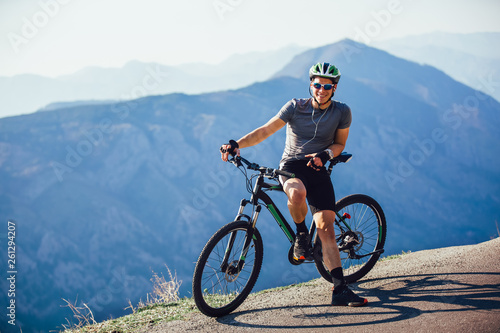 Portrait of mountain biker with helmet and sunglasses listening to music and smiling.