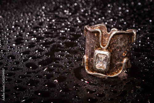 elegant silver crown ring on dark background with water drops