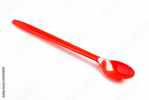 Foto A single long and unused shiny red plastic spoon deliberately and artistically set on a plain white background