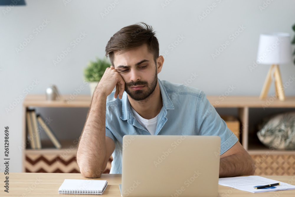 Tired student or employee working with laptop, doing boring job Tired student or employee working with laptop, doing boring job