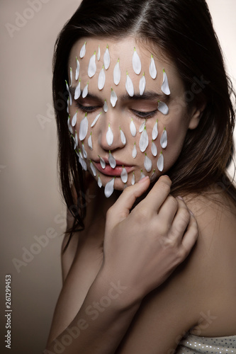 Model looking down while showing face covered in white petals