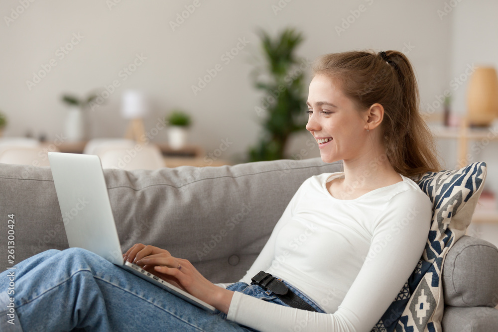 Happy smiling woman sitting on sofa and using laptop at home Happy smiling woman sitting on sofa and using laptop at home