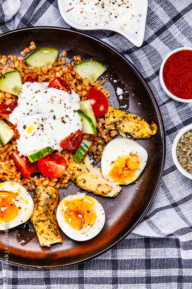 Grilled chicken meat with groats and boiled egg on wooden table Grilled chicken meat with groats and boiled egg on wooden table