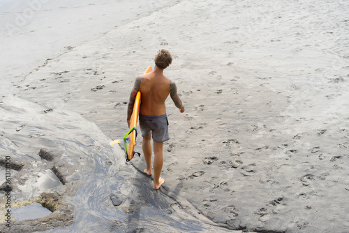 Photography Attractive male surfer in tattoos on the ocean with an orange bright longboard surfboard