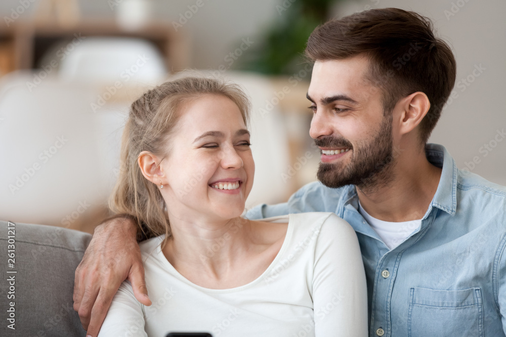 Happy smiling man and woman cuddle, using phone together