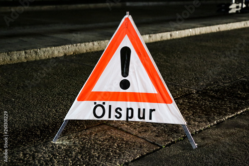 Warnung Schild in der Nacht auf der Fahrbahn nach Verkehrsunfall wegen Ölspur photo