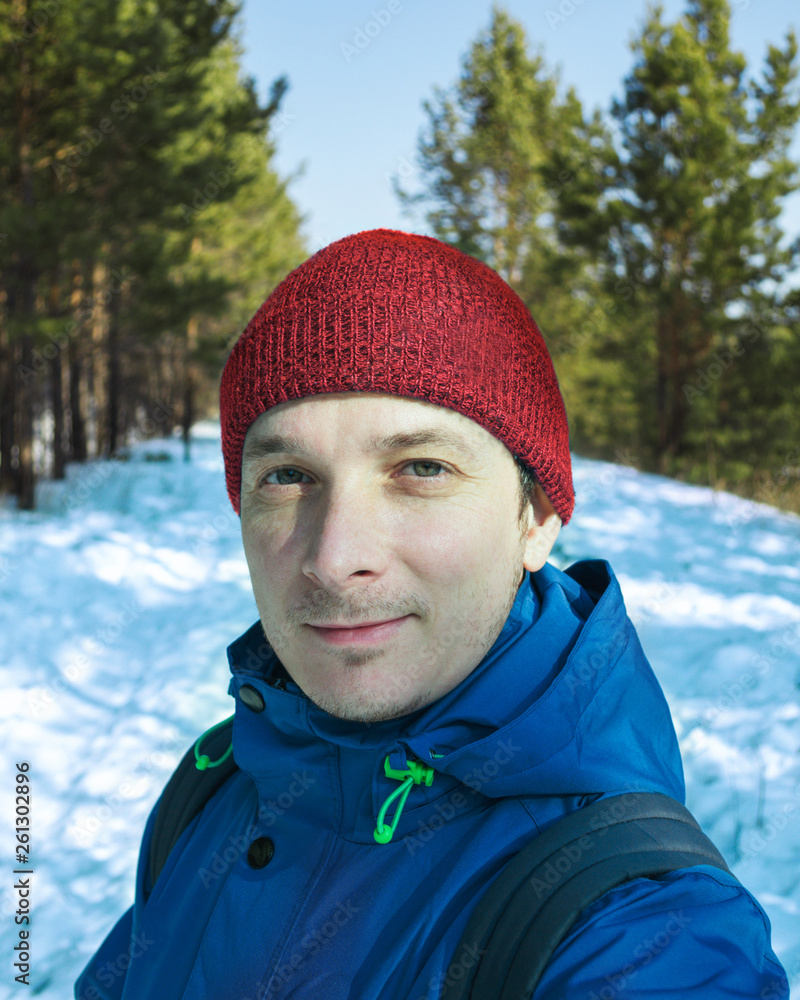man smiles in blue jacket and red cap in winter outside man smiles in blue jacket and red cap in winter outside