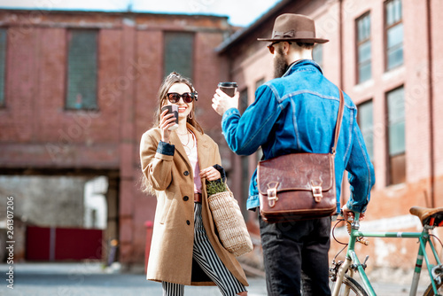 Stylish young man and woman having fun, standing together with retro bicycle outdoors on the industrial urban background