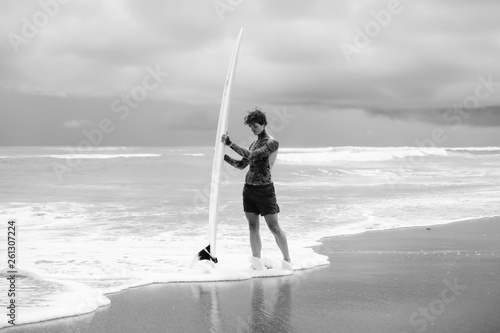 Photography Attractive male surfer in tattoos on the ocean with an orange bright longboard surfboard